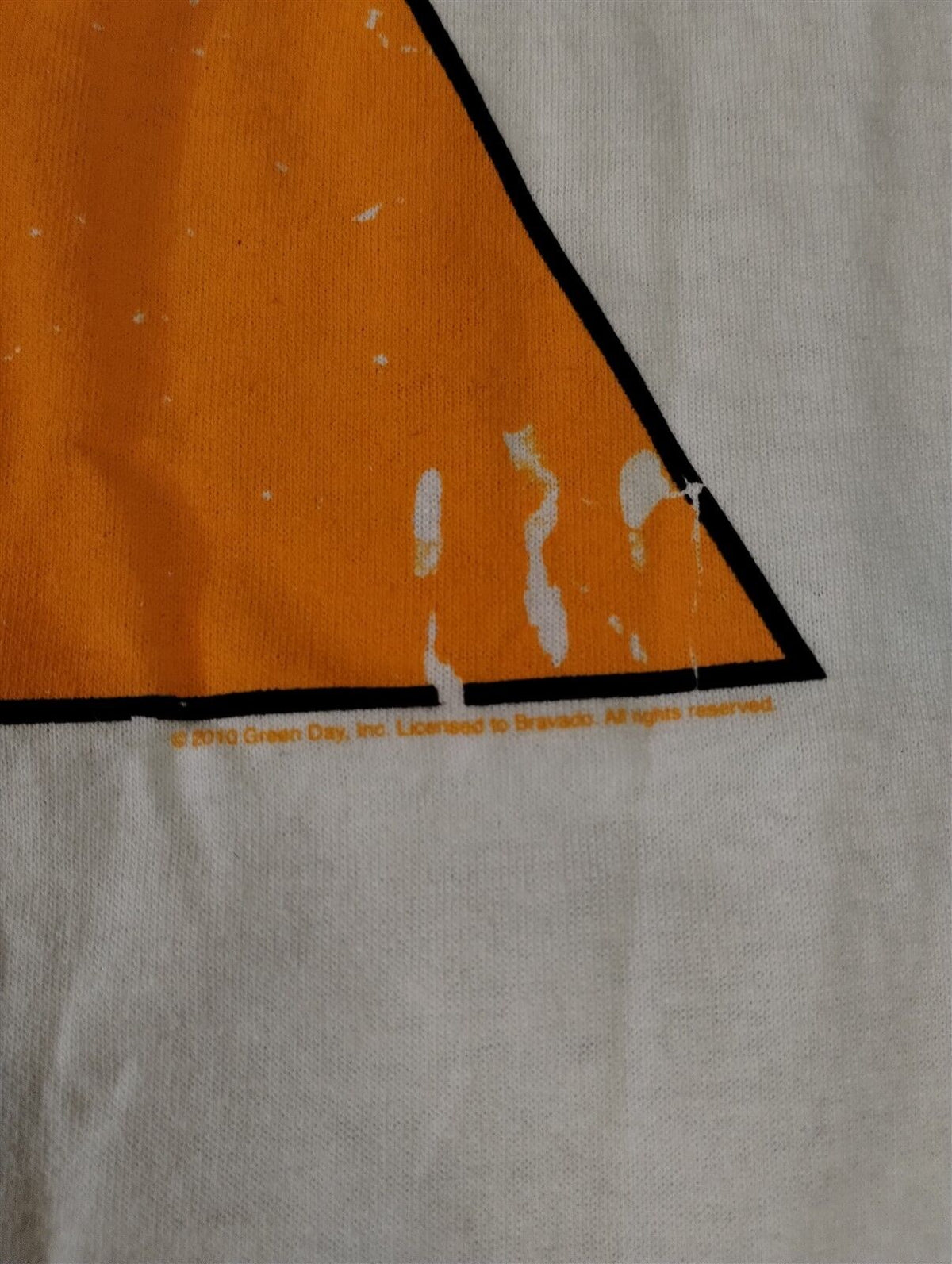 Throwback Rack vintage 2010 Green Day band t-shirt detail showing the orange triangle graphic and copyright text