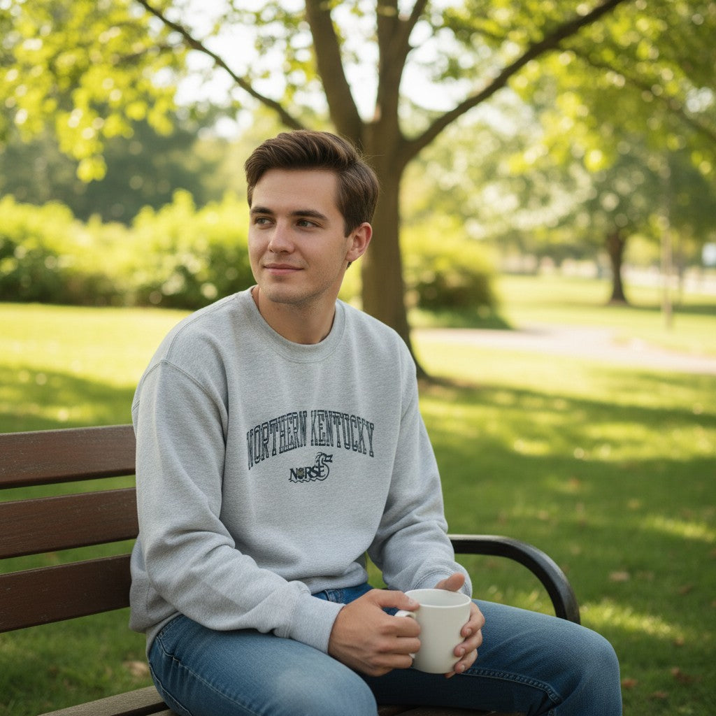 Throwback Rack grey crewneck sweatshirt with Northern Kentucky Norse logo. Model wears it with blue jeans.