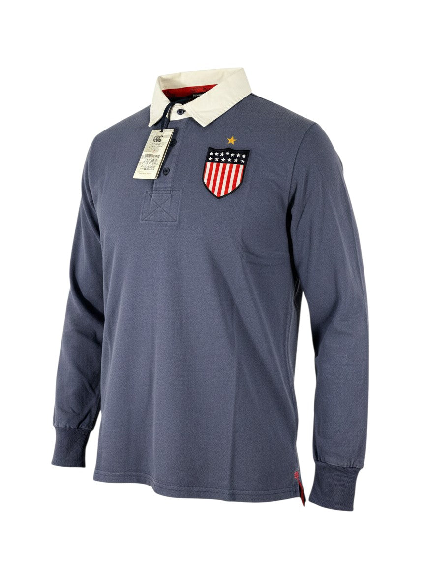 Throwback Rack USA Canterbury blue long-sleeve rugby polo shirt with white collar and US flag shield patch on chest.